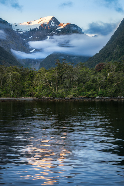 Mountain and glacier reflected in the water at sunset in beautiful Harrison Cove at Milford Sound, Fiordland National Park, New Zealand South Island.