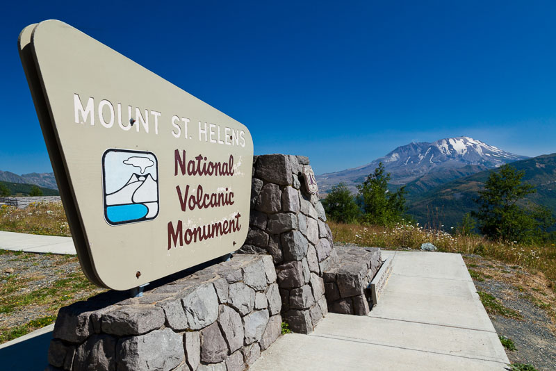 A sign signalling the entrance to the Mount St. Helen's National Volcanic Monument with Mt St. Helens in the background in Washington