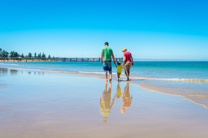 Famiy walking along Glenelg Beach, one of the best Adelaide day trips