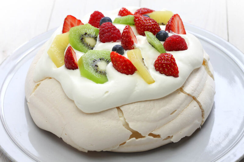 A homemade pavlova with strawberries and kiwifruit on top, the quintessential NZ desserts